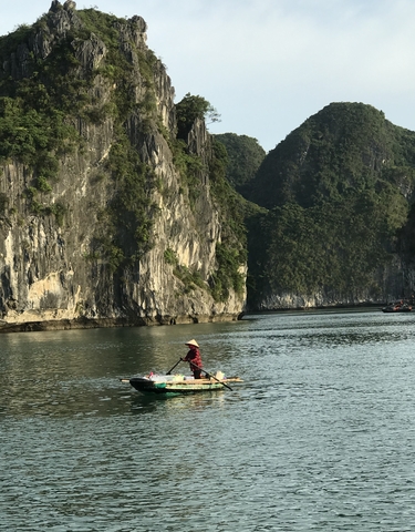 A person paddling a boat through a stunning limestone karst landscape.