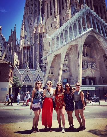 Group of women posing in front of a large, intricate structure.