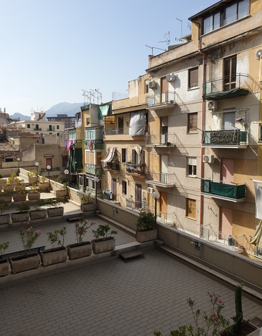 Residential buildings with balconies and a mountainous backdrop.