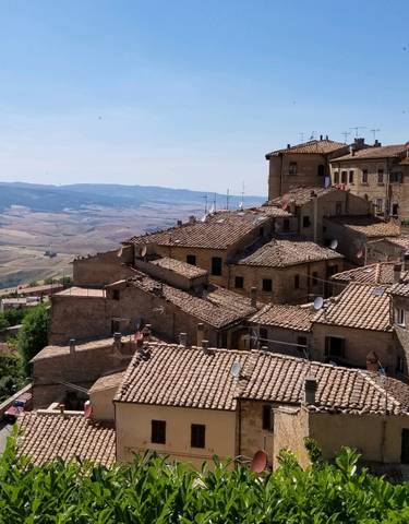 Hillside view of a picturesque medieval town with terracotta rooftops.