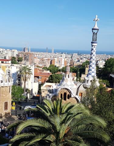View of Park Güell with colorful architecture and a city skyline.