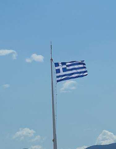 Greek flag waving against a blue sky.