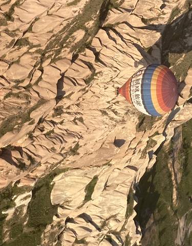 Hot air balloon flying over a rocky landscape.