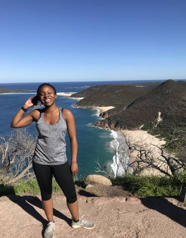 Person happily posing with a stunning coastal view.