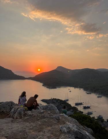 Sunset view over a bay with yachts and mountains.