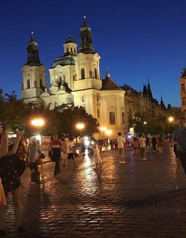 People enjoying an evening in a European city with a lit church facade.