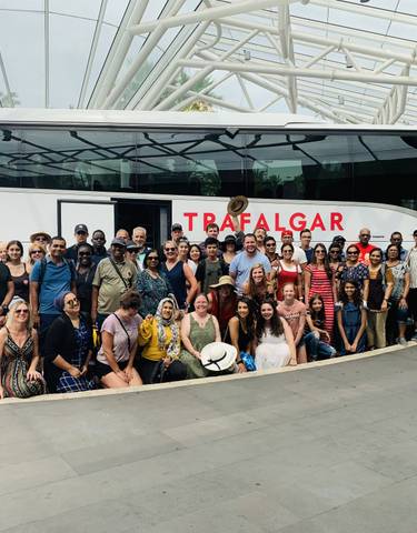 Group photo in front of a tour bus labeled 'Trafalgar'.
