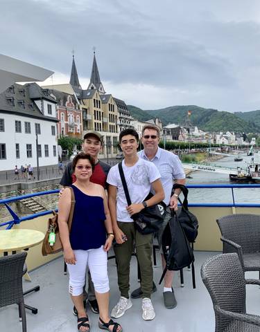 Group of people posing in front of a river with buildings in the background.