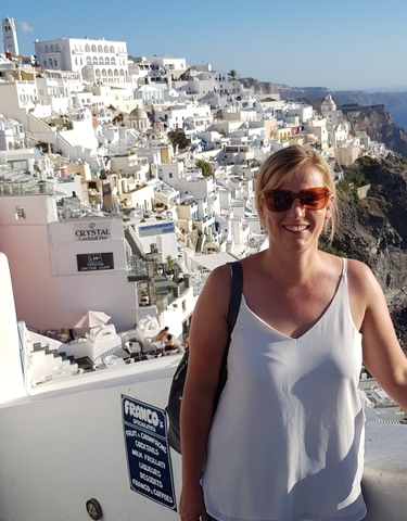 Smiling woman in front of white buildings on a hillside.