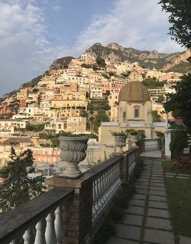 Positano cityscape with colorful hillside buildings and a dome.