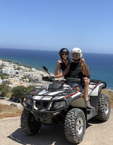 Couple riding an ATV overlooking a seaside village.