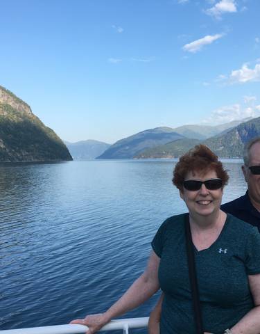 Couple posing on a ferry with mountains and water in the background.