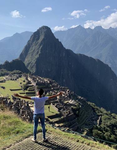 Person with arms outstretched enjoying the view of Machu Picchu.
