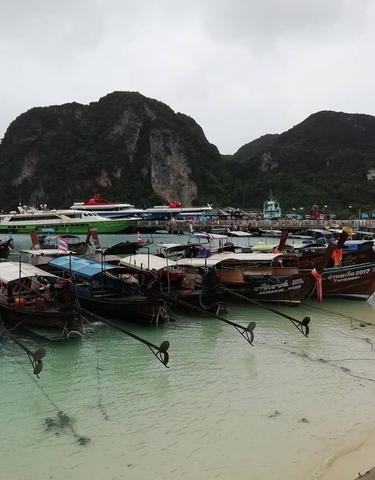 Boats docked at a pier with cliffs in the background.