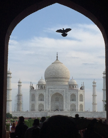 The Taj Mahal framed by an archway with a partly cloudy sky.