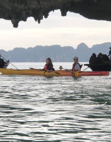 People kayaking on a calm sea with karst formations.