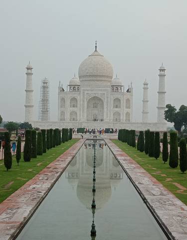 The Taj Mahal with people walking along the garden pathway.