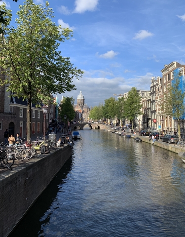 Picturesque canal with a large church and boats on a sunny day.