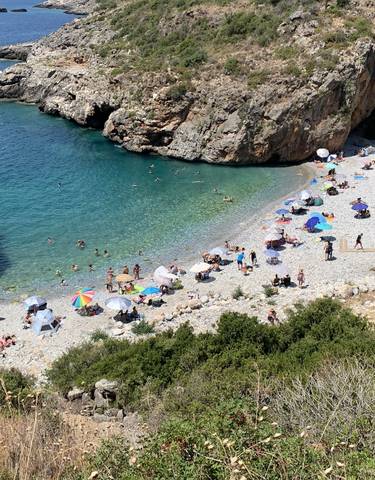 Pebble beach with umbrellas and swimmers