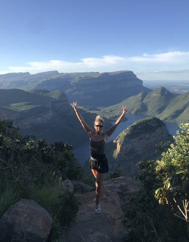 Person posing on a mountainous area with stunning views of lakes and peaks.