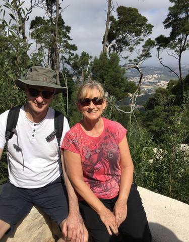 A couple posing in front of a scenic landscape view.