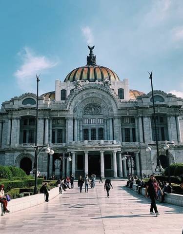 A grand building with a dome and statues in an urban park setting.