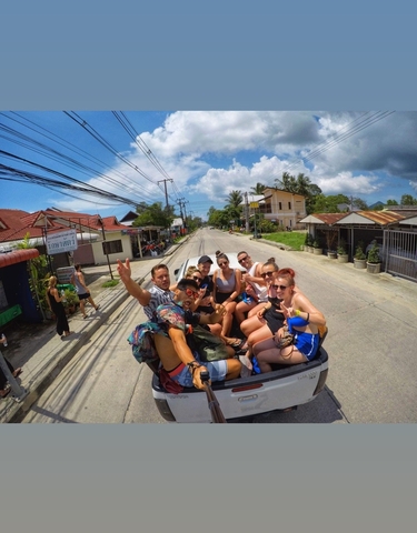 Group of people on the back of a truck enjoying a ride in a tropical town.