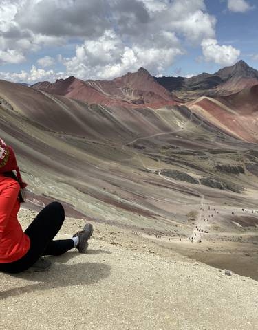 Woman sitting at Rainbow Mountain, Peru.