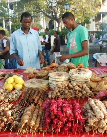 Street food vendors at a market with various grilled items.