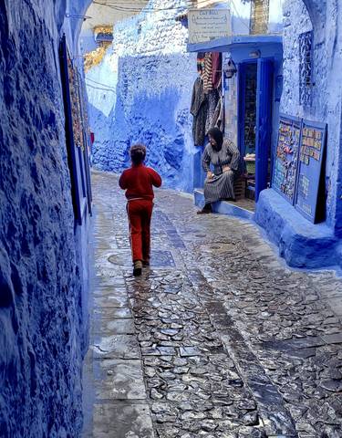 A child walking in a narrow blue-painted street.