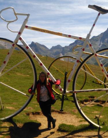 A person next to giant bicycle sculptures in the mountains.