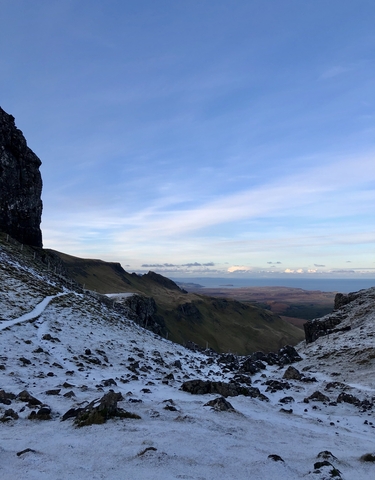 Snow-covered mountain pass with ocean and islands in the distance.