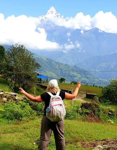 Person with arms raised in front of a breathtaking mountain view.