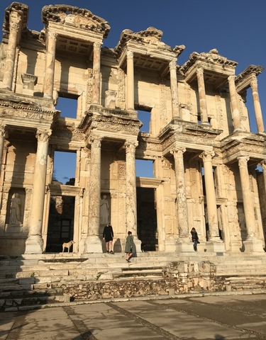 Facade of an ancient structure with people walking in front.