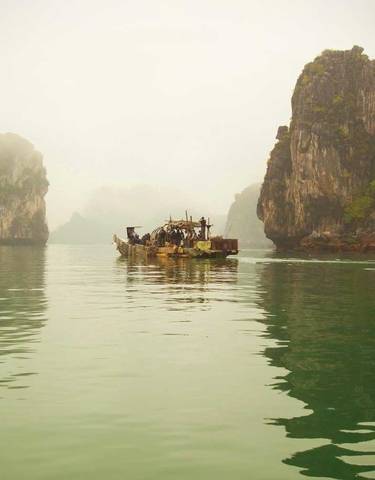Misty bay with rock formations and a boat.