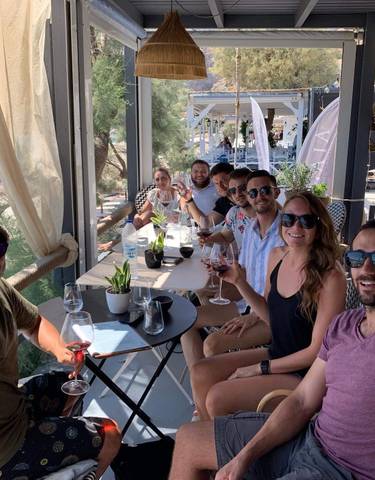 Group of people sitting at an outdoor cafe with a sea view.