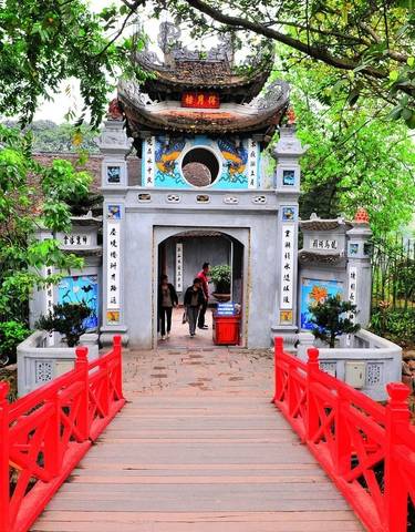 Entrance to Ngoc Son Temple with a red bridge and greenery.