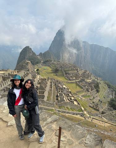 Two people smiling at Machu Picchu with a view of the ruins.