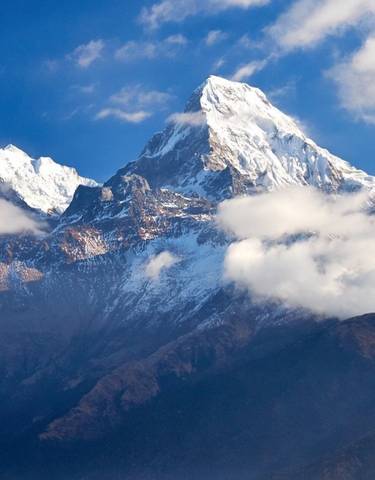 Snowy mountain peak with clouds surrounding.