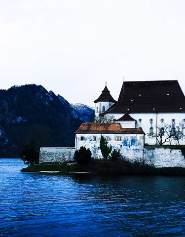A castle near a lake with mountains.