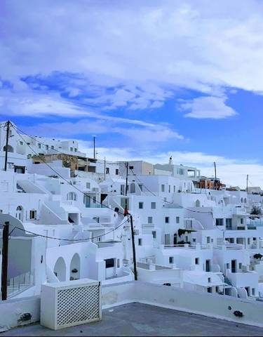 Panoramic view of white buildings on a hillside under a blue sky.