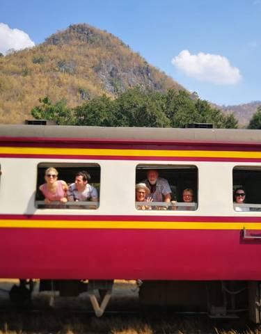 Group of people leaning out of a colorful train window.