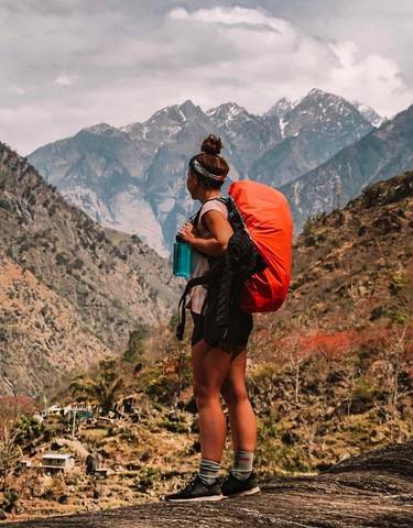 Person with large backpack standing in a mountainous landscape.