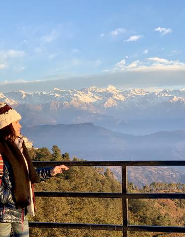 Person enjoying a mountain view with snow-covered peaks.