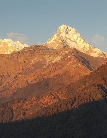 Sunlit mountain peaks with clear sky backdrop.