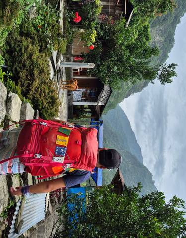 Hiker with backpack on stone path, with mountainous background.