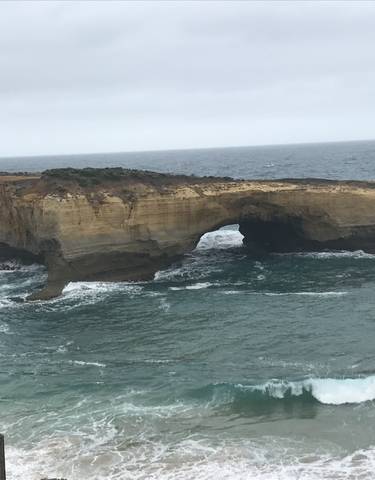 A rock formation in the ocean with people observing.