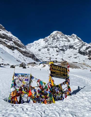 Annapurna Base Camp in the snow with colorful flags.