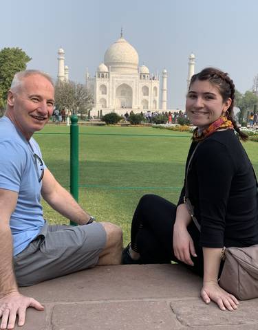 Two people sitting with the Taj Mahal in the background.
