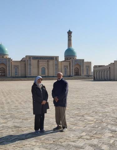 Two people standing in front of a historical building with large domes.